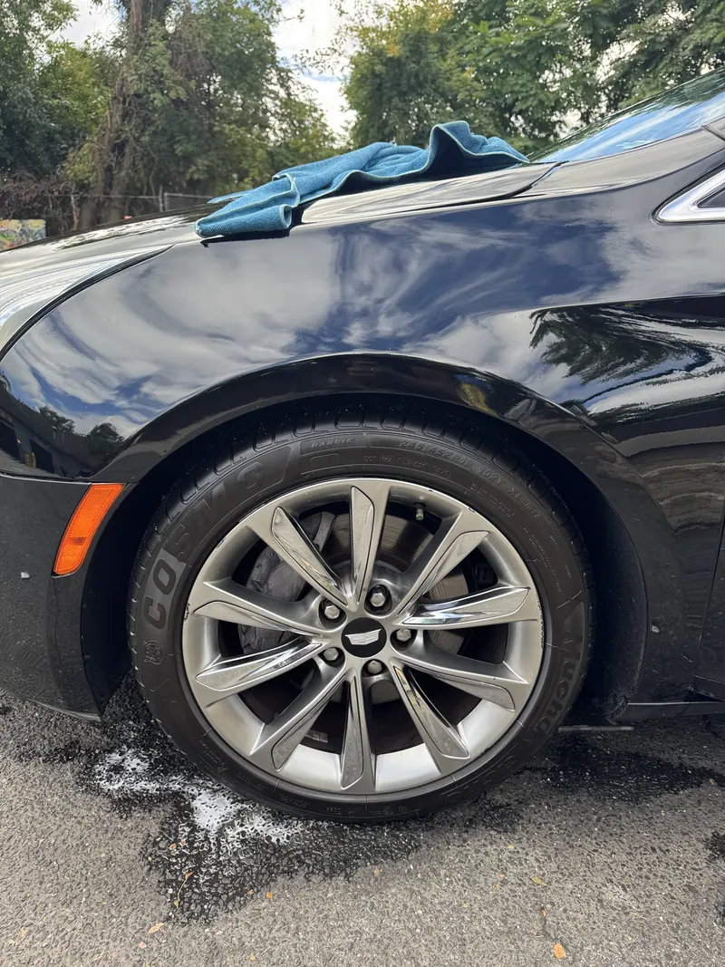Glossy black Cadillac fender and a clean silver alloy wheel